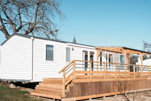 a white tiny house with a wooden deck at Pivoine Camping Belle-Vue 2000 in Berdorf