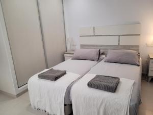 two beds in a white room with towels on them at La Perla Blanca in Benijófar
