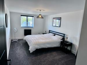a white bedroom with a bed and two windows at New 2 Bed Apartment in Royston High St in Royston