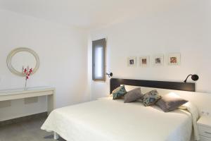Un dormitorio blanco con una cama y un espejo. en Ses Viñas De Cas Baixero, en La Mola 40 fotos más