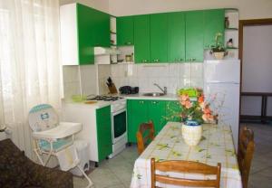 a kitchen with green cabinets and a table with a vase of flowers at Apartments Paulina in Postira