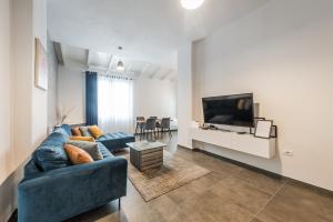 Royal Hill Apartments by PS في دوريس: غرفة معيشة مع أريكة زرقاء وتلفزيون بشاشة مسطحة