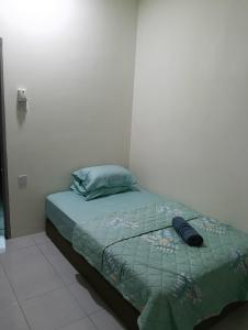 a bed with a green comforter in a room at The Welcome Mat Homestay in Seri Iskandar +4 photos