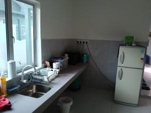 a kitchen with a sink and a white refrigerator at The Welcome Mat Homestay in Seri Iskandar