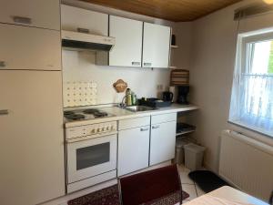 a kitchen with white cabinets and a stove and a sink at Ferienwohnung in Münchenbernsdorf
