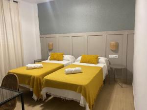 two beds with yellow sheets in a room at Apartamentos Turísticos La Terraza* in Las Cabezas de San Juan