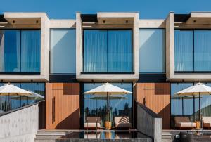 an external view of a building with tables and umbrellas at Greenvale Park Villas by Coastalbliss in Khlorakas