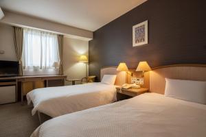 ein Hotelzimmer mit zwei Betten und einem Schreibtisch in der Unterkunft Hotel Global View Iwaki in Iwaki