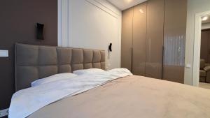 una camera da letto con un letto grande con lenzuola bianche di Nova ApartHotel a Chişinău