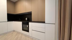 una cucina con armadi bianchi e forno nero di Nova ApartHotel a Chişinău