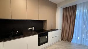 una cucina con mobili bianchi e un piano di lavoro nero di Nova ApartHotel a Chişinău