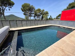 a swimming pool with a bench next to a fence at La Gacélyte Piscine privée joli bas de villa in Carqueiranne