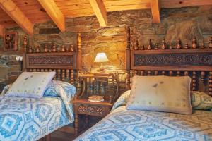 a bedroom with two beds and a stone wall at Casa Rural Tio Eloy in Fabero
