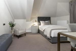 a white bedroom with a bed and a chair at Reea Boutique Hotel in Târgovişte