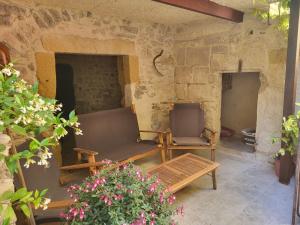a patio with two chairs and a couch and flowers at La grange in Aspères