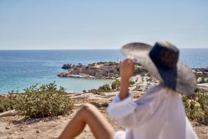a woman in a hat looking at the ocean at Althea Boutique Hotel - Adults Only in Amoopi