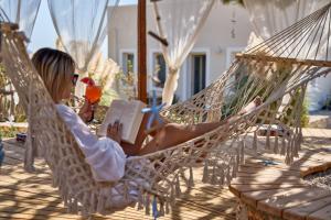 a woman sitting in a hammock reading a book at Althea Boutique Hotel - Adults Only in Amoopi
