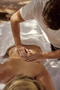 a man getting a back massage on a bed at Althea Boutique Hotel - Adults Only in Amoopi