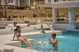 a man and a woman sitting in a swimming pool at Althea Boutique Hotel - Adults Only in Amoopi