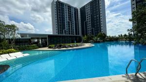 a large blue swimming pool with chairs and buildings at Bandar Gamuda Cove Splash Mania Fully Air Con Suite, 42700 Banting in Banting