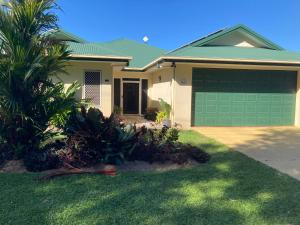 a house with a green garage door and a palm tree at Sunriser in Kurrimine Beach