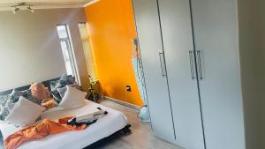 Un dormitorio con una cama con una pared naranja. en Roloma Property, en East London