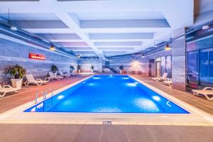 a large swimming pool in a building with chairs at Radisson Residences Vadistanbul in Istanbul