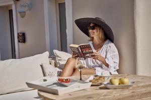 a woman sitting on a bed reading a book at Althea Boutique Hotel - Adults Only in Amoopi