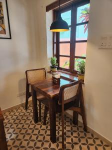 a dining room table with two chairs and a lamp at Ederra Stays & Cafe in Panaji