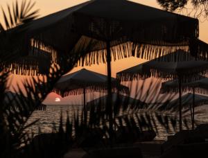 a beach with umbrellas and the sun setting at Oniro Boutique Hotel in Toroni