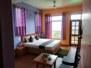 a bedroom with a bed and a table and window at New Summer Capital in Shimla