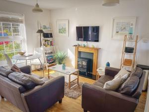 een woonkamer met twee banken en een open haard bij Mallow Cottage in Camber