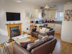 een woonkamer met twee banken en een open haard bij Mallow Cottage in Camber