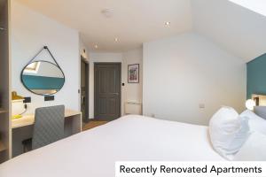 a bedroom with a bed and a desk and a mirror at Holyrood Aparthotel in Edinburgh