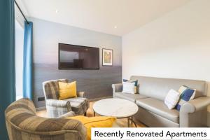 a living room with a couch and two chairs and a tv at Holyrood Aparthotel in Edinburgh