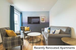 a living room with a couch and chairs and a tv at Holyrood Aparthotel in Edinburgh