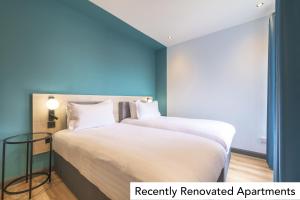 a bedroom with a bed with white sheets and blue walls at Holyrood Aparthotel in Edinburgh