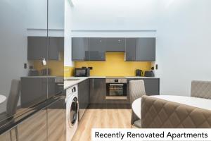 a kitchen with stainless steel appliances and yellow walls at Holyrood Aparthotel in Edinburgh