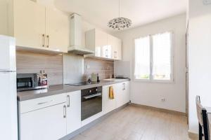 a white kitchen with white cabinets and a window at Chez Jean-Louis in Tavernes