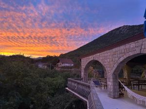 a sunset over a brick bridge with a table and chairs at Skadar Lake Family Resort in Rijeka Crnojevića