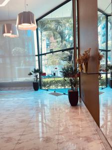 a lobby with potted plants and large windows at Hotel Enseada Boa Viagem in Recife