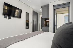 a bedroom with a white bed and a tv on the wall at One Calais Luxury Apartments in Cape Town