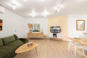 Una sala de estar con un sofá verde y una mesa. en T2 Calme absolu - Coeur Toulouse - Saint Cyprien - climatisation - Terrasse arborée, en Toulouse
