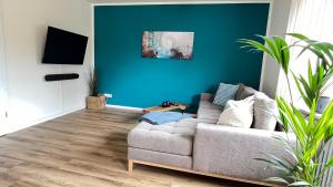 a living room with a couch and a blue wall at Großes Apartment für 6 - Gasgrill Citynah Parken in Lippstadt