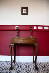 a wooden table in front of a red wall at Cozy Alty Flat Walk to Market Tram to City in Broadheath +4 photos