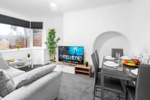 a living room with a couch and a table with a television at 4 Bedroom House - Accommodates 7 - Garden - Parking - Netflix - Wifi - 559T in Birmingham
