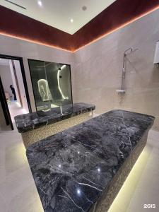 a bathroom with a large black marble bath tub at Oasis апартаменты возле Триумфальной арки in Astana