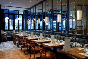 eine Reihe von Tischen in einem Restaurant mit Fenstern in der Unterkunft Sloane Square Hotel in London