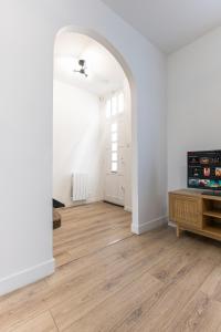 an empty living room with an archway and wooden floors at La Mancelle - 6 Personnes - Plein cœur du Mans in Le Mans