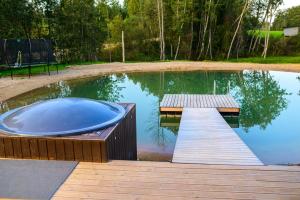 a small pool with a wooden dock and a hot tub at Ojakalda Puhkemaja in Piigaste